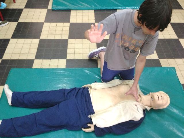 Initiation d'un enfant au massage cardiaque sur mannequin